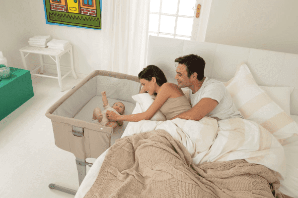 sidosäng med baby i bredvid stor säng med mamma och pappa i