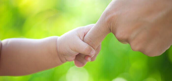Bebishand håller om vuxens finger