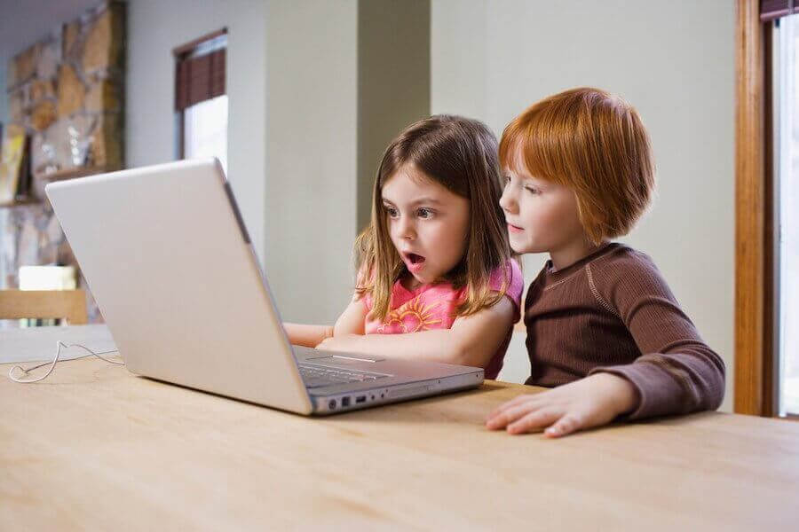 Pojke och flicka framför laptop