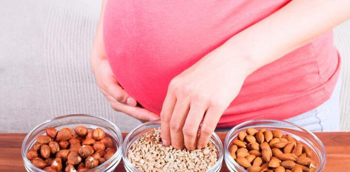 gravid kvinna vid skålar med frön och nötter