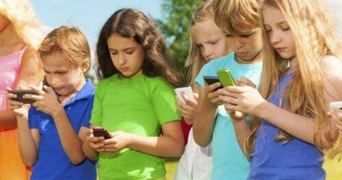 Barn står i rad och tittar på sina smartphones