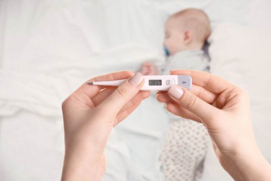 febertermometer med baby i bakgrunden