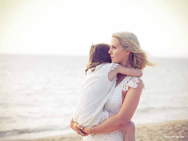 Mamma bär barn på strand
