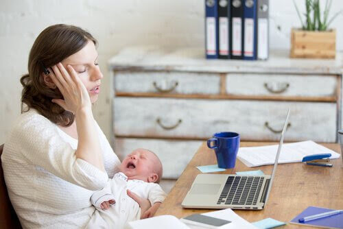 mamma med skrikande baby framför skrivbord