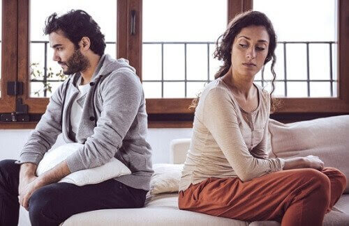 man och kvinna sitter på säng och ser ut att vara ovänner