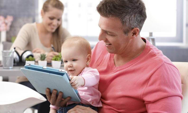 Pappa med bebis som tittar på surfplatta