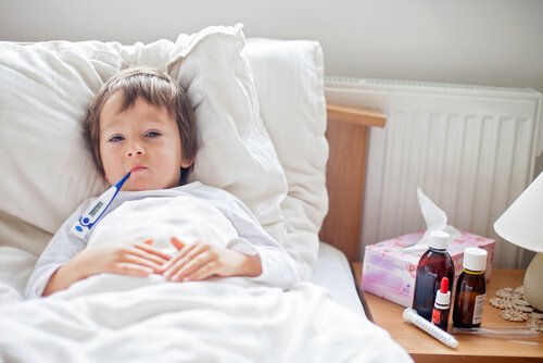 Barn ligger i säng med febertermometer i munnen.