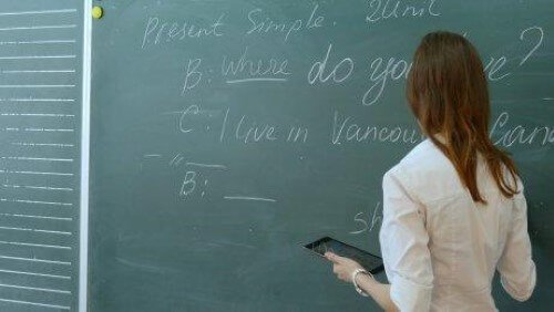 Engelska lärare skriver på svarta tavlan.