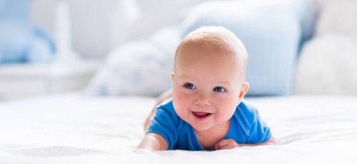 Bebis ligger på mage och ler.