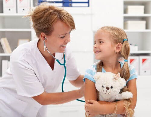 Barn håller i sin nalle under ett besök hos doktorn.