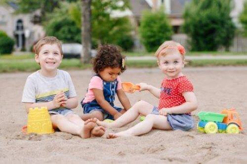 Barn övar på sin sociala kompetens genom lekar i sandlådan.