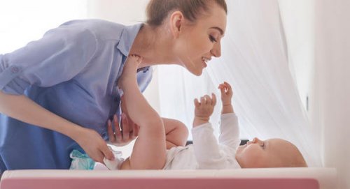 Mamma byter blöja på sitt barn.