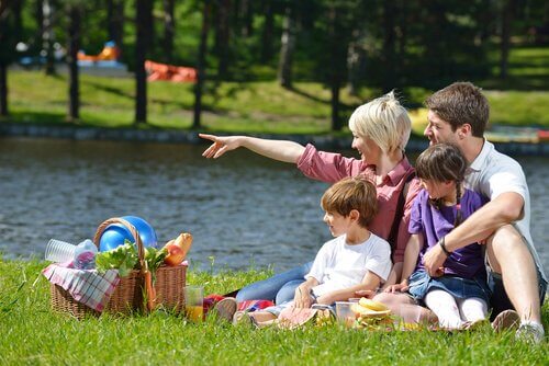Familj sitter i gräset och njuter av en picknick.