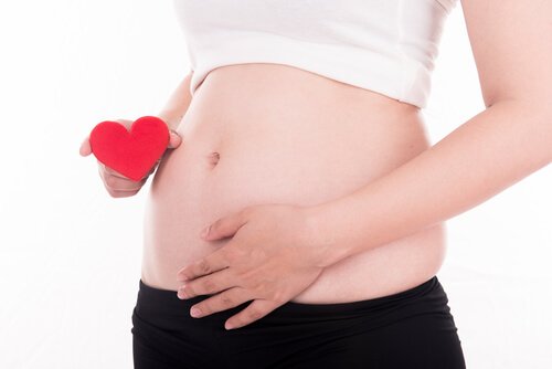 Gravid kvinna i första trimestern med hjärta i handen.