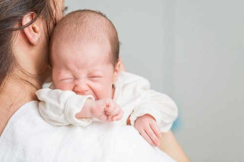 En kvinna håller en gråtande bebis.
