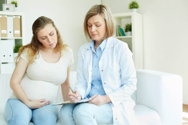 gravid kvinna talar med läkare