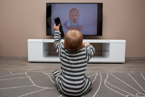 att lära sig språk i barndomen: baby med fjärrkontroll framför tv