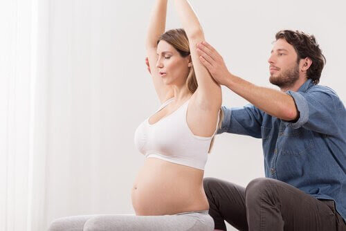 man stöttar gravid kvinna när hon gör övningar