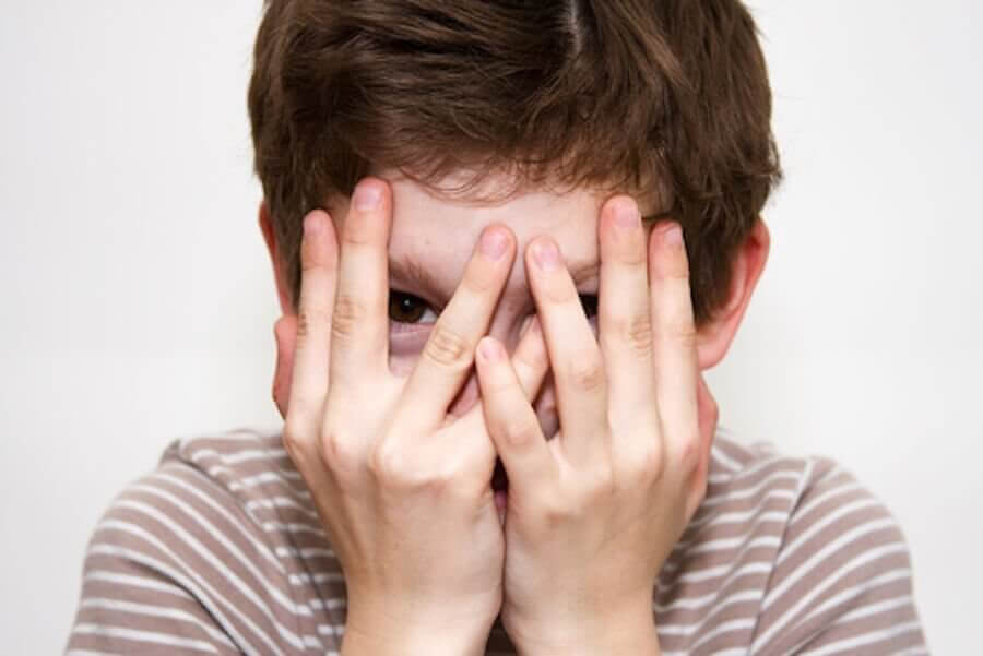 Blyghet under barndomen: blygt barn håller händerna för ansiktet
