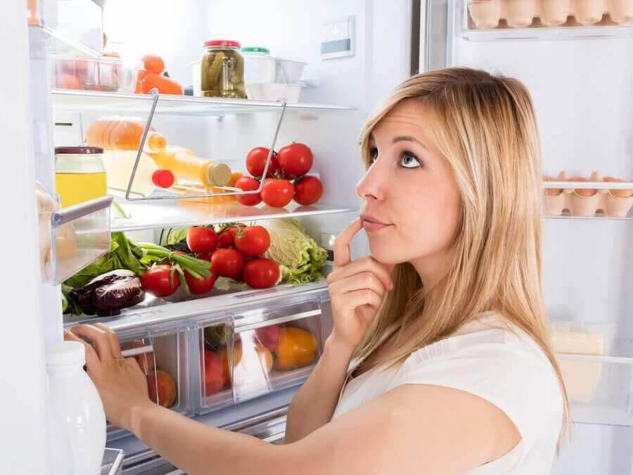 tankfull kvinna framför öppet kylskåp