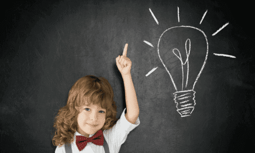 att lära sig språk i barndomen: pojke framför svart tavla med glödlampa ritad på