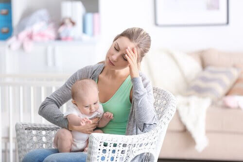 kvinna ser trött ut och håller i den baby