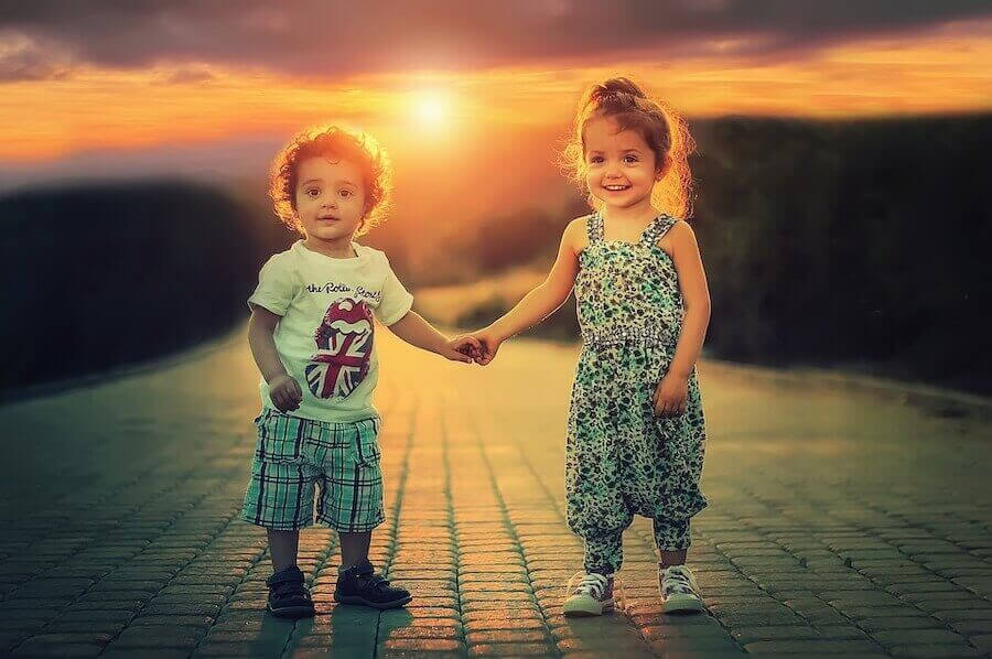 liten pojke och flicka håller handen i solnedgång