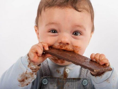 mycket kladdig och glad baby äter choklad