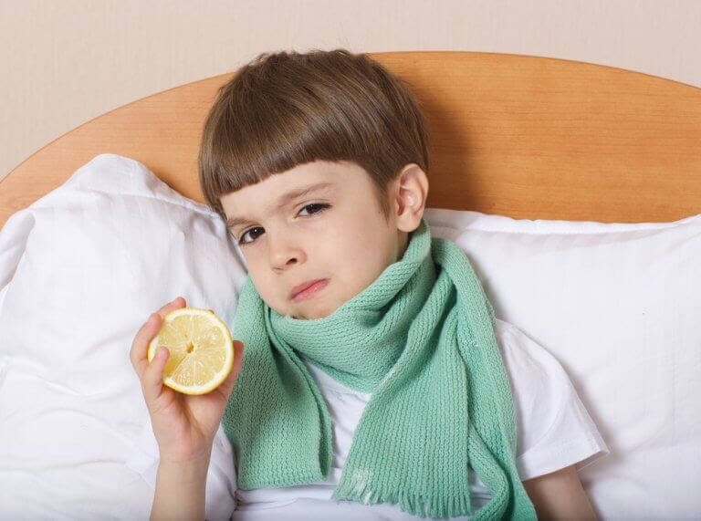pojke med halsduk i säng håller upp en citron
