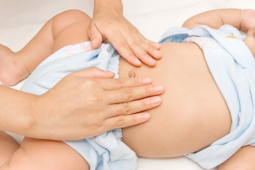 händer undersöker mage på baby