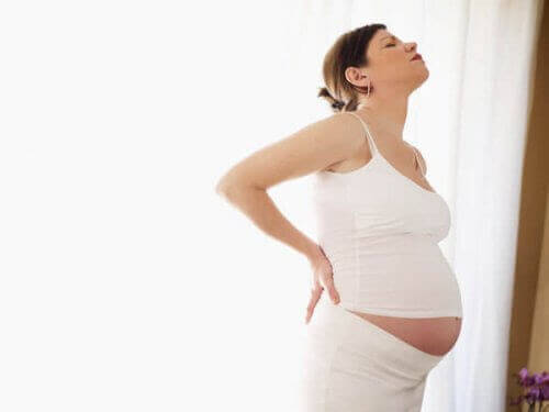 lätta och komplicerade förlossningar: gravid kvinna håller sig för ryggen