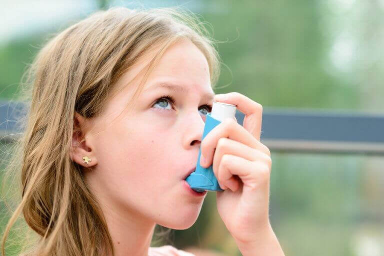 Flicka med astma använder inhalator