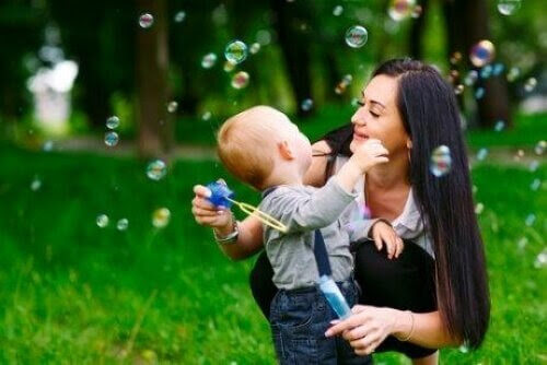 sex månader gammal baby i mammas famn tittar på såpbubblor