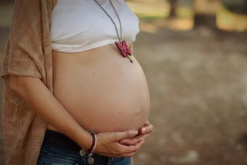Gravid kvinna med händerna på magen.