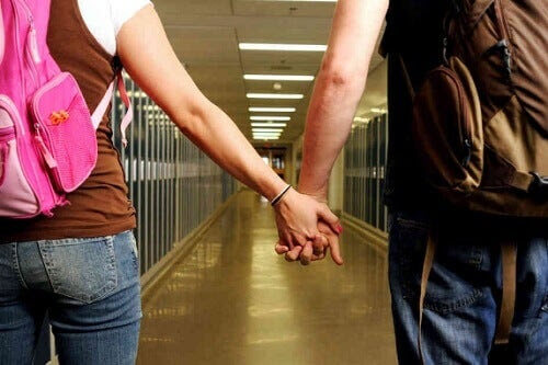 tonåringar håller händerna i skolkorridor