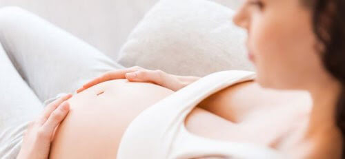 gravid kvinna håller sig för magen