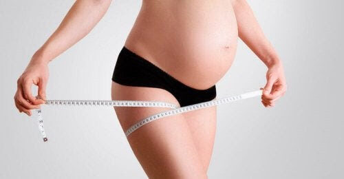 gravid kvinna mäter sitt lår