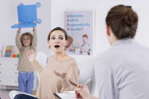 mamma och lärare diskuterar barn som håller stol över huvudet