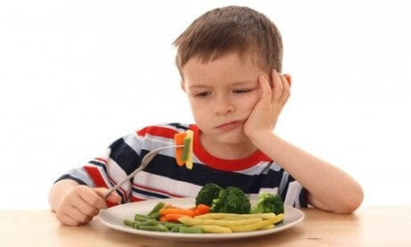 undernäring och näringsbrist under barndomen: pojke tittar uppgivet på sin mat