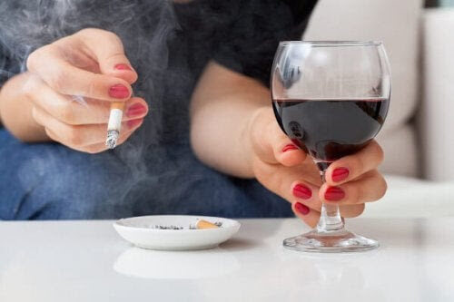 alkohol kan påverka din baby: gravid kvinna håller i ett glas vin och en cigarrett