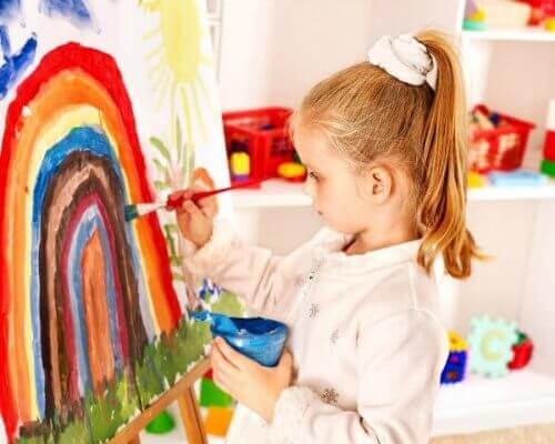 vikten av konst: flicka målar en regnbåge