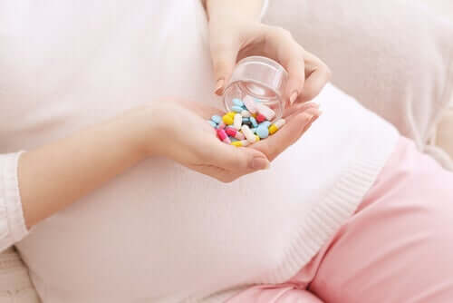 Gravid kvinna med vitaminer i handen.
