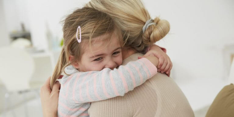 Flicka som kramar mamma.
