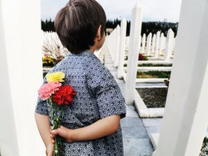 pojke med blommor bakom ryggen på kyrkogård