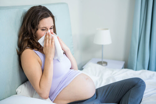 förkylningar under graviditeten: gravid kvinna snyter sig