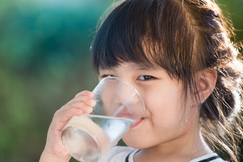 Urinvägsinfektioner hos barn: flicka dricker ett glas vatten