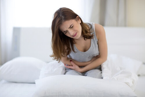 infertilitet hos kvinnor: kvinna ligger på säng och håller sig för magen