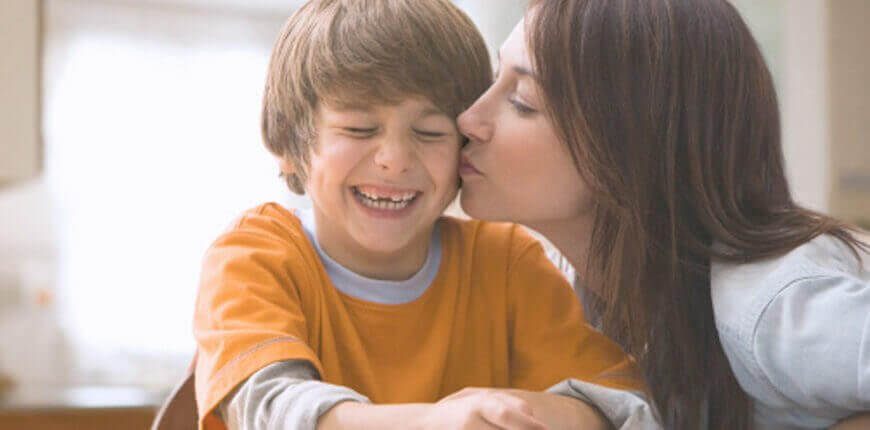 glad pojke får en puss av sin mamma