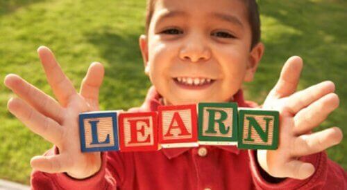 Ett barn håller klossar som bildar ordet "learn".