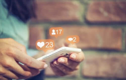 Kan föräldrar kontrollera sina barns sociala medier? händer håller telefon med symboler som svävar ovanför